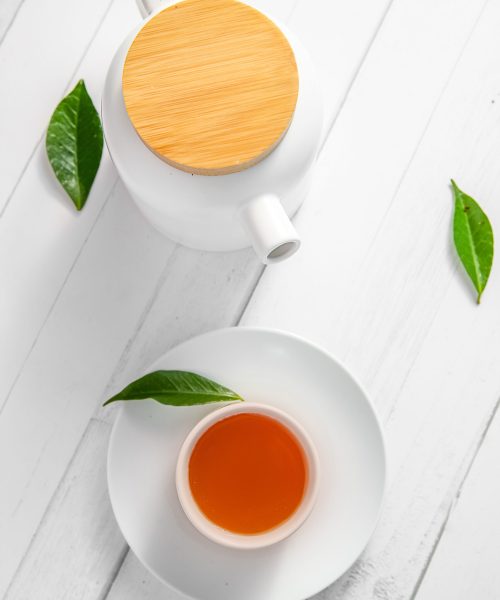 top view or flatlay with herbal tea in a cup and teapot on white wooden background, teatime ceremony, traditional chinese or japanese tea. High quality photo